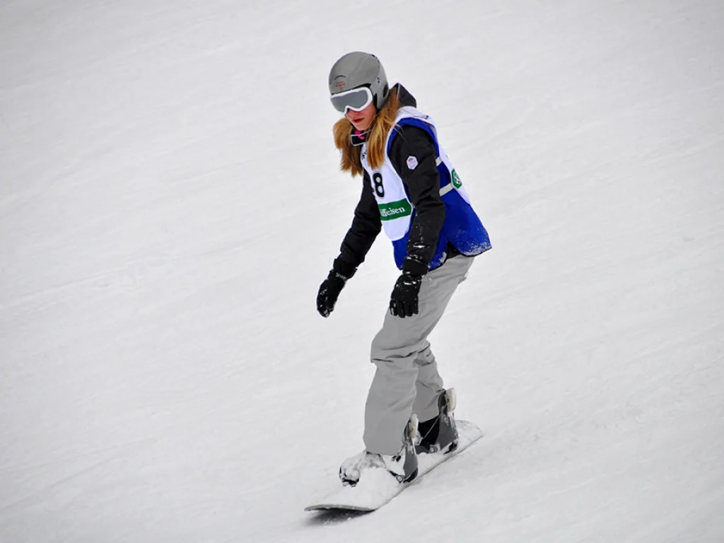 Snowboarderin in heller Hose auf der Strecke.